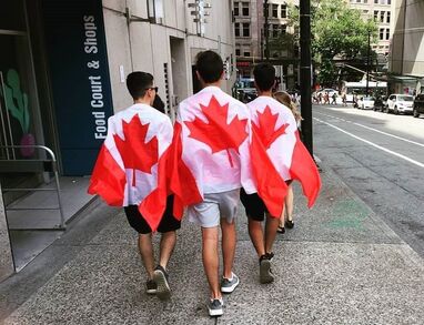 My boys walking on street in Vancouver on Canada Day, wearing Canada flag capes.e