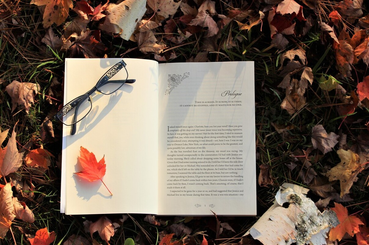 image of book lying on a bed of autumn leaves open to prologue